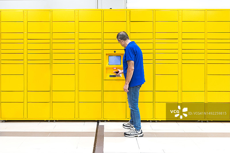 穿着蓝色Polo衫的老年人用手机扫描代码取包裹图片素材