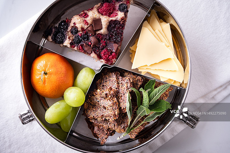 可重复使用容器中的纯素午餐（饼干、奶酪、薄煎饼、水果）图片素材