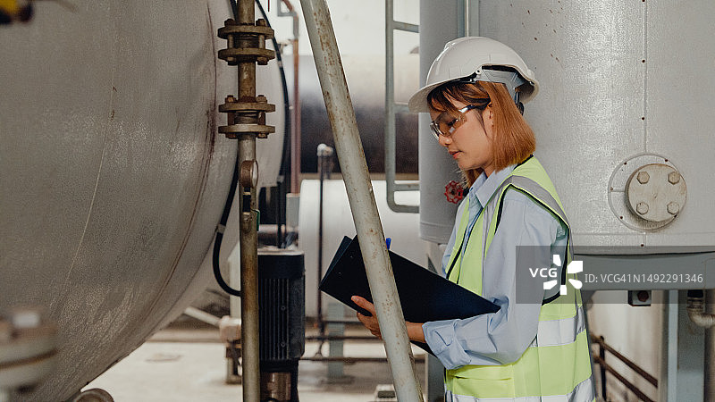 戴着安全帽的年轻亚洲女工程师在化工厂检查蒸汽锅炉图片素材