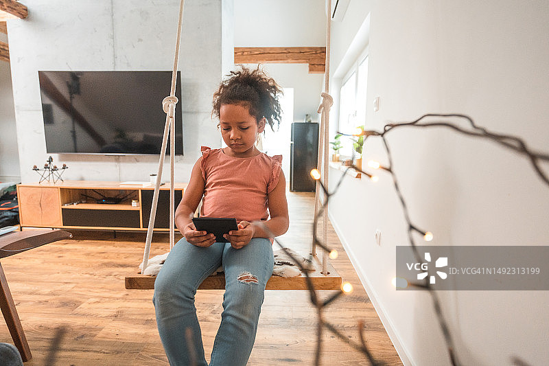 在家阅读电子书的混血小女孩图片素材