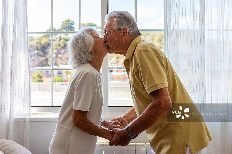 快乐的老年夫妇手牵着手亲吻图片素材