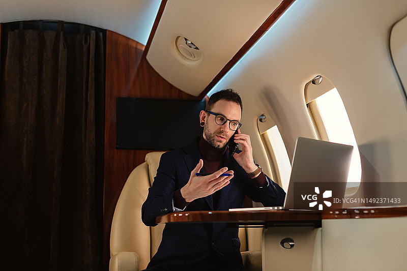 商务人士在私人飞机内使用手机工作特写图片素材
