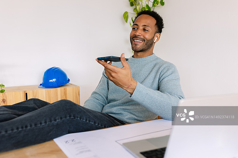 快乐的年轻建筑设计师工程师在家庭办公室工作时用手机交谈图片素材