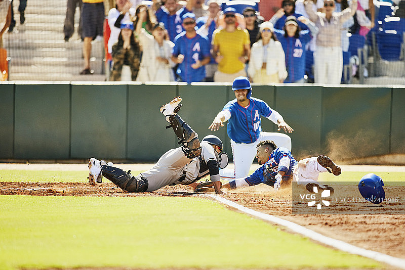 棒球比赛中，跑垒员滑垒躲避接球手图片素材