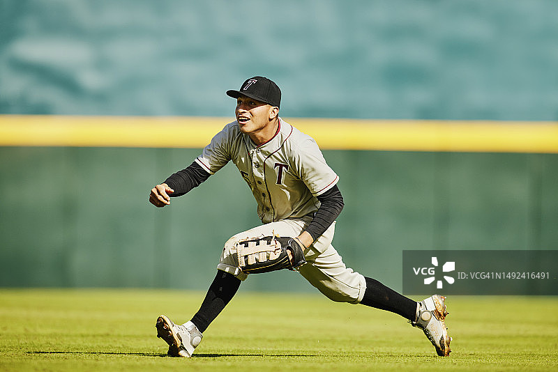 棒球比赛中，外野手跑去接球的广阔景象图片素材