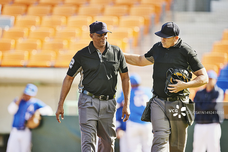 棒球比赛前，裁判员在球场上讨论的中景广角镜头图片素材