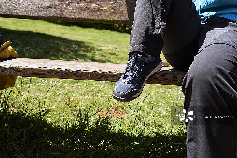 休闲装女孩坐在木凳上的鞋子特写，正面视角图片素材
