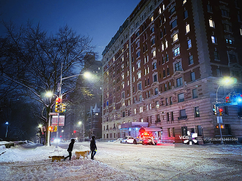 一对情侣在傍晚的暴风雪中穿过上西区中央公园西路遛狗图片素材