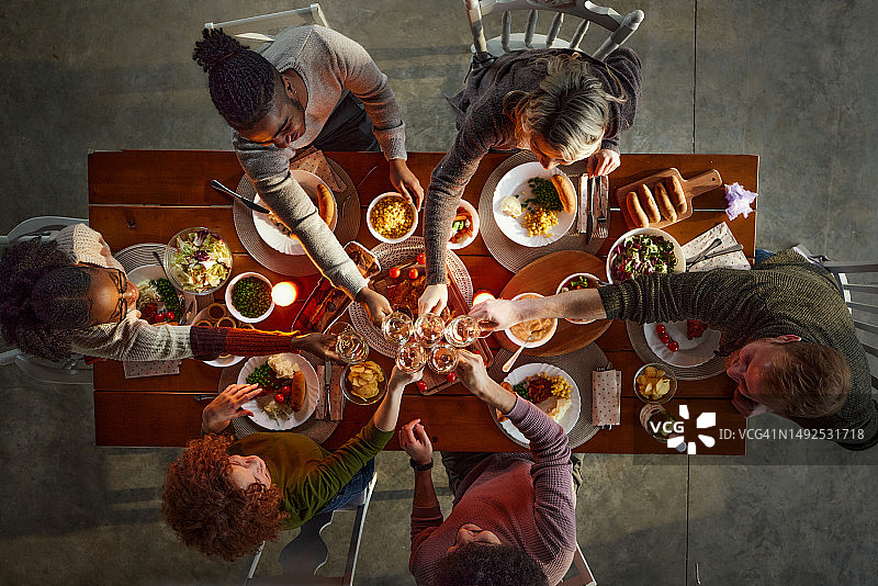 午餐时餐桌旁快乐的朋友们举杯庆祝（俯视角度）图片素材
