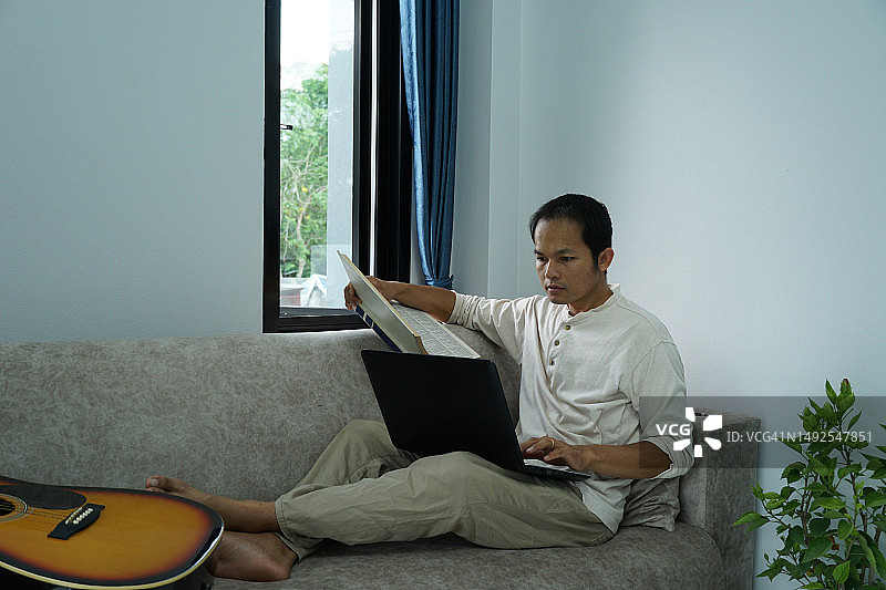 亚洲男人在家用笔记本电脑上网学习图片素材