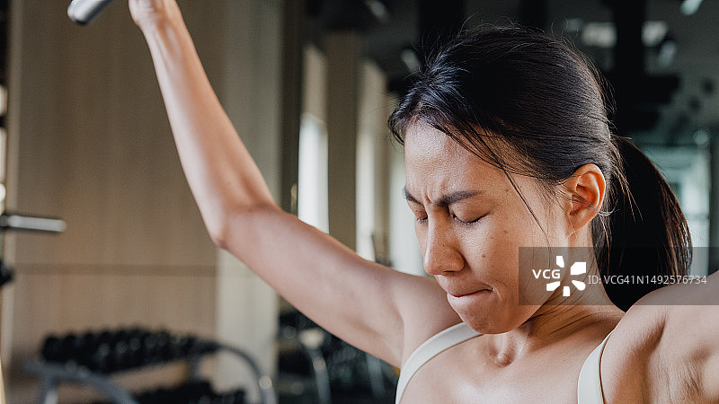年轻的亚洲女子在现代健身房的器械上积极进行引体向上训练特写图片素材