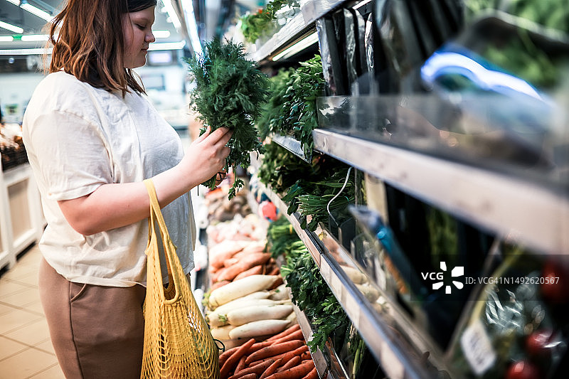 Z世代的理性消费：超重少女在有机市场选择草药和蔬菜图片素材