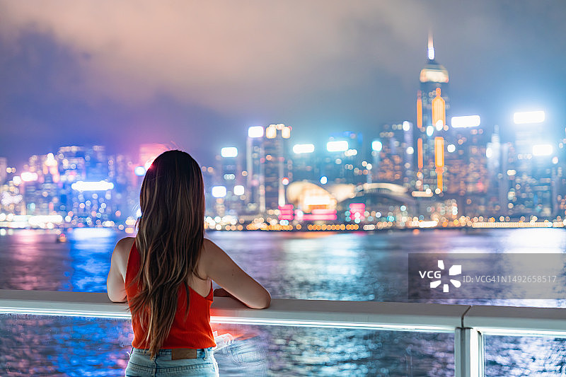 夜间，年轻的亚洲旅行者站在金融区现代企业摩天大楼旁图片素材