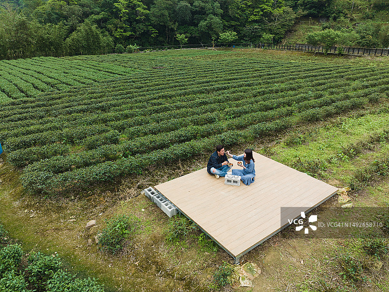 年轻合伙人在茶田旁用金属饭盒享用午餐图片素材