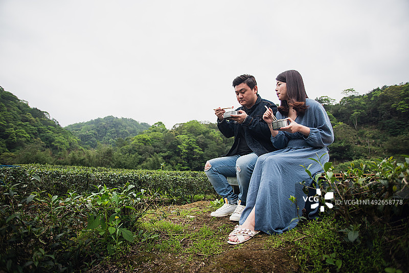年轻合伙人在茶田旁用金属饭盒享用午餐图片素材