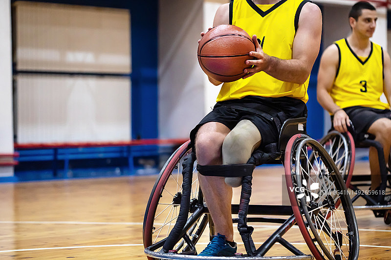 坐在轮椅上，在室内运动场上 holding basketball 的运动员图片素材