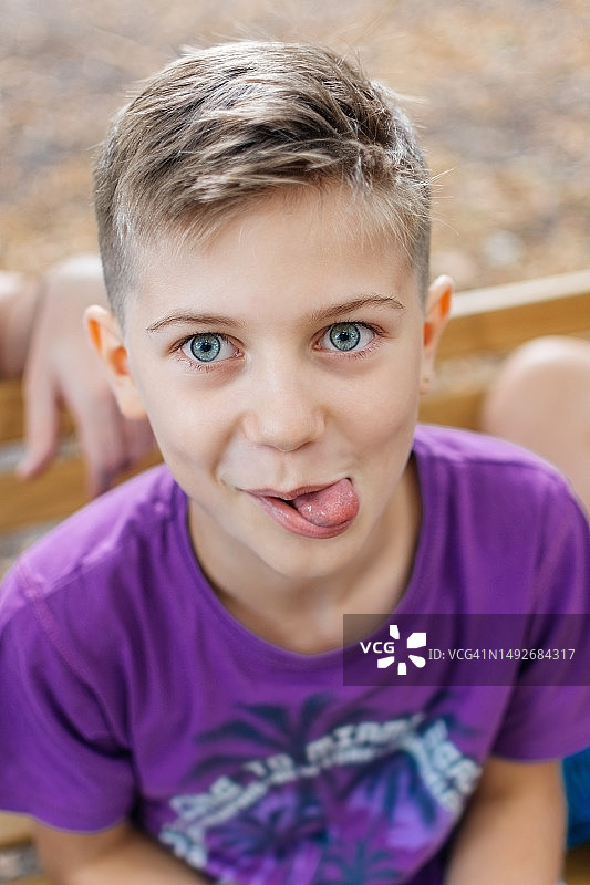 公园长椅上吐舌头的可爱小男孩图片素材