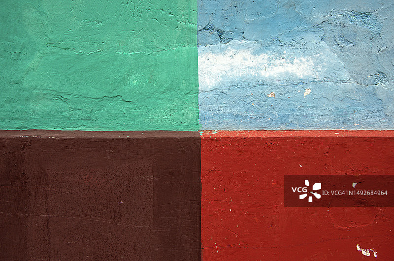 浅绿色、深棕色、浅蓝色和深红色象限的粗糙不平的粉刷墙图片素材