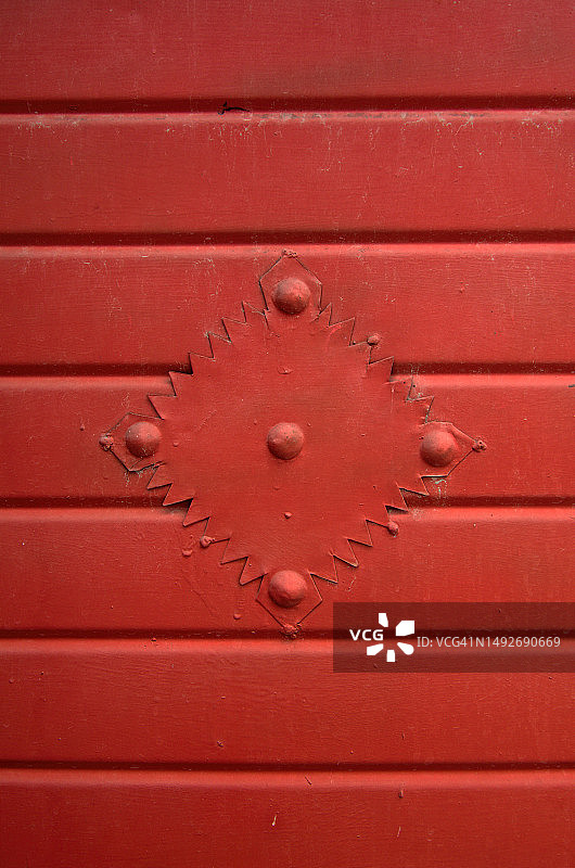 锈红色凹槽金属门上的锯齿边钻石形铆钉装饰图片素材