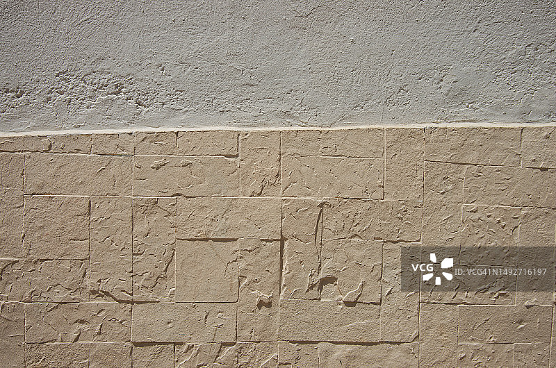 殖民建筑外观，白色油漆的纹理灰泥墙，底部是米色石砖图片素材