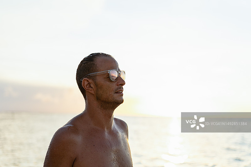 日落时分在海滩上放松的年轻男子肖像图片素材