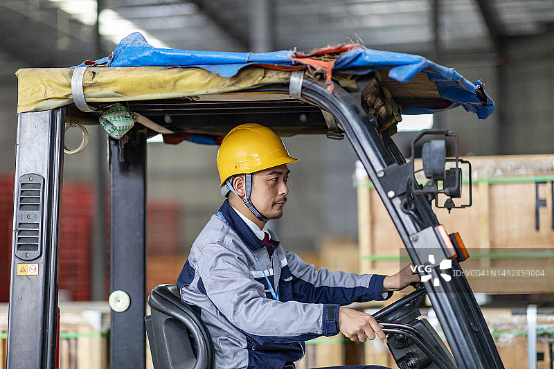 在配送仓库中驾驶叉车的亚洲仓库工人图片素材