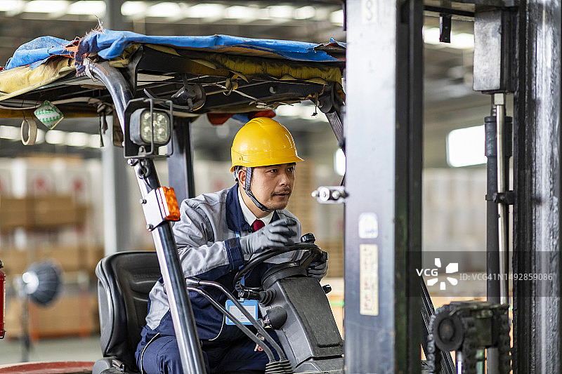 在配送仓库中驾驶叉车的亚洲仓库工人图片素材
