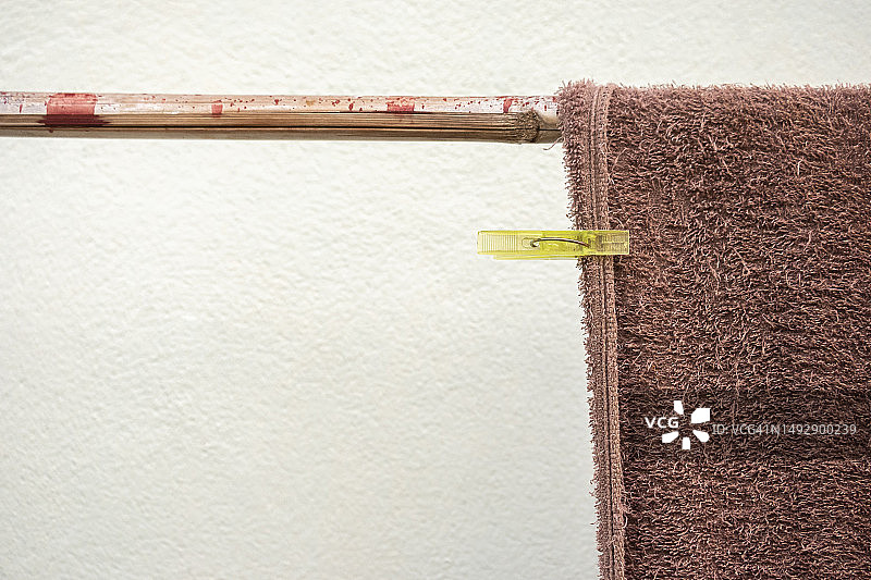 用晾衣夹将毛巾固定在着色木栏杆上，白色墙壁背景图片素材