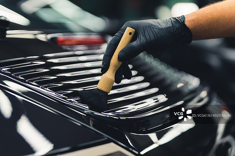 戴黑色手套的男人擦拭车背的特写镜头图片素材