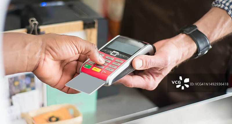 男人在咖啡馆用信用卡进行非接触式支付图片素材