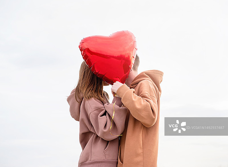 手持红色气球在北京户外拥抱亲吻的年轻情侣图片素材