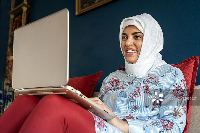 使用笔记本电脑进行远程办公的快乐阿拉伯穆斯林女性，土耳其图片素材
