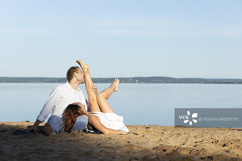 快乐的跨国情侣在海滩上，白人男子亲吻拉丁裔女子图片素材
