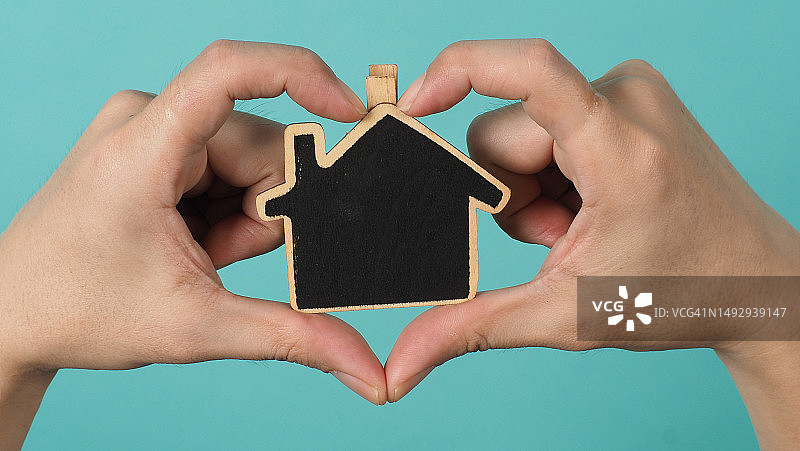 手中握着的小木屋，代表家庭关爱概念，泰国曼谷图片素材