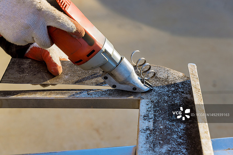 工人用双刃电动剪刀切割金属图片素材