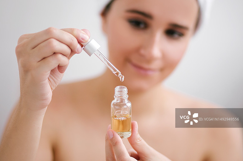 年轻美女肖像，头裹毛巾，手持面部精油图片素材