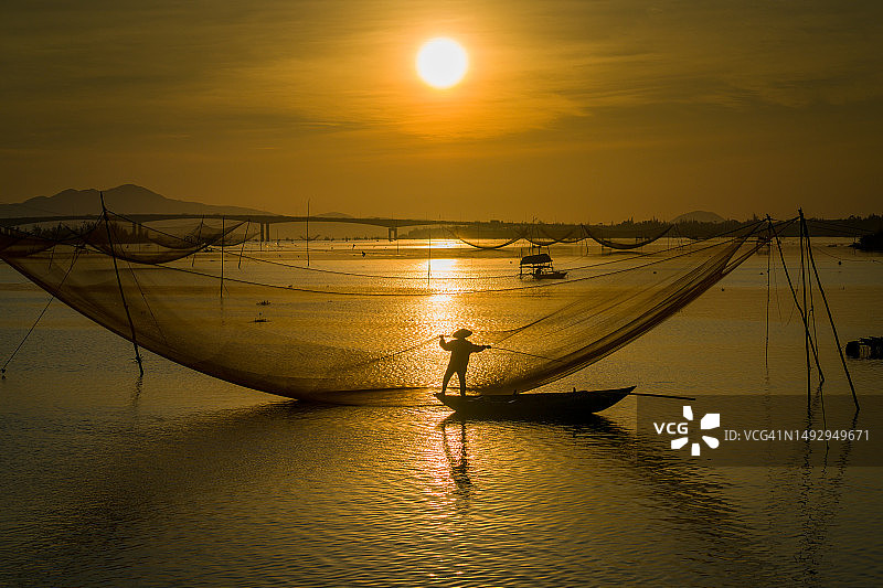 越南日落时分，渔夫在渔网中的剪影图片素材