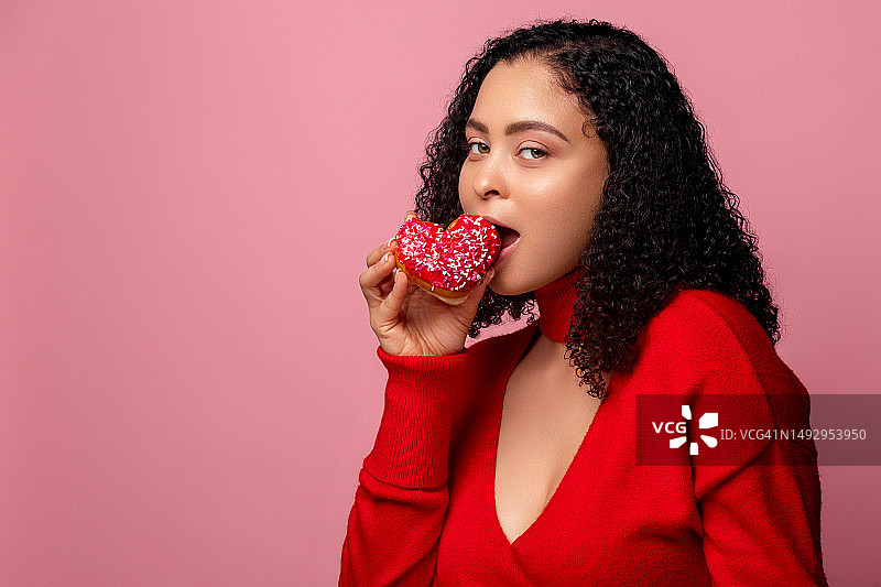 在粉红色背景下吃巧克力的女人肖像，美国佛罗里达州基西米图片素材