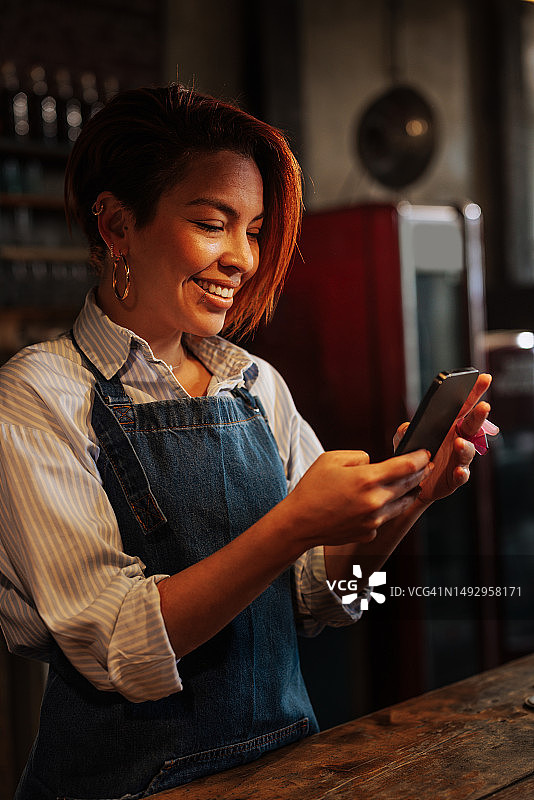 迷人的年轻女服务员微笑发短信图片素材