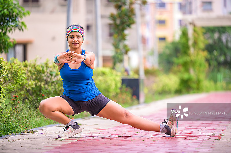 年轻健身女性正在做弓步侧身运动，进行腿部肌肉锻炼图片素材