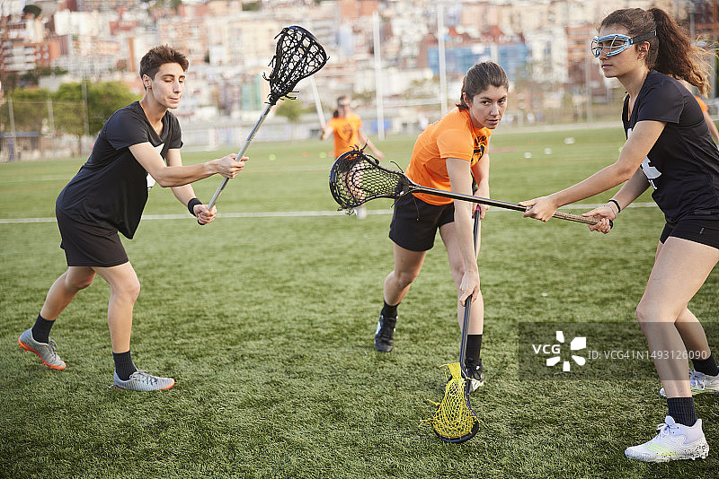 激烈的对抗：女子长曲棍球运动员在两名防守队员中精准射门图片素材