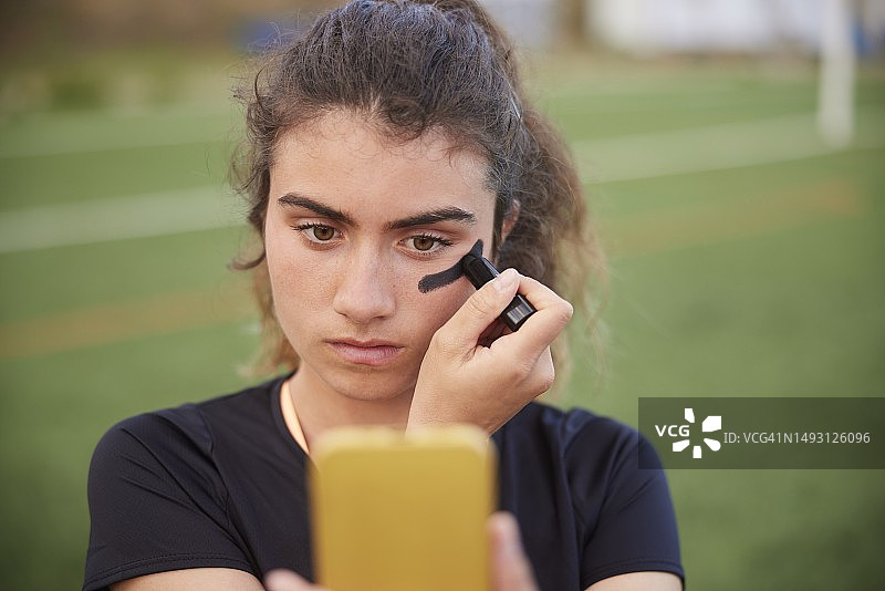 科技助力：女子长曲棍球运动员使用智能手机当镜子图片素材