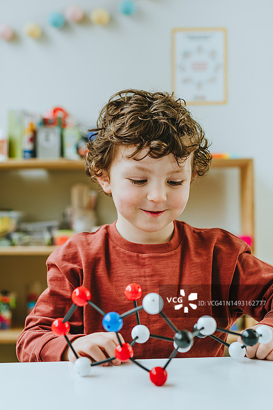 幼儿园里拿着分子模型玩具的学龄前儿童图片素材