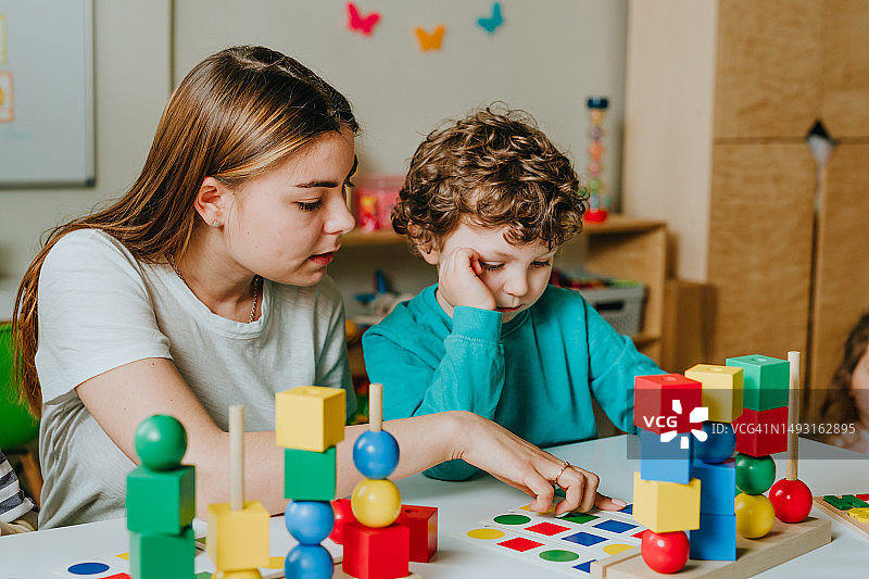 女老师在幼儿园帮助小男孩按颜色整理积木图片素材