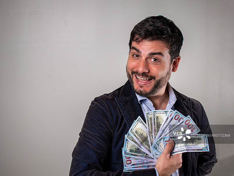 商务男士手持大量钞票，面带微笑图片素材