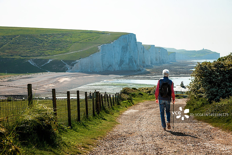 年长的男人在通往英国乡村七姐妹悬崖的乡间小路上徒步旅行图片素材