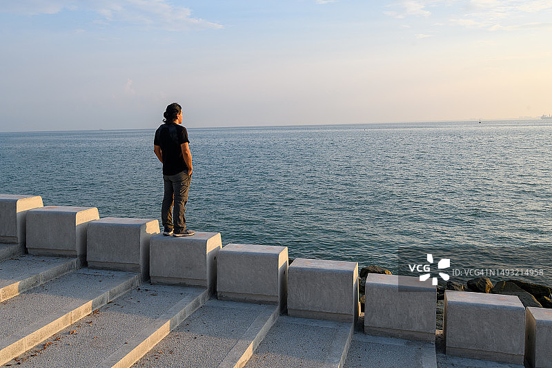 男人在防波堤顶端欣赏大海图片素材