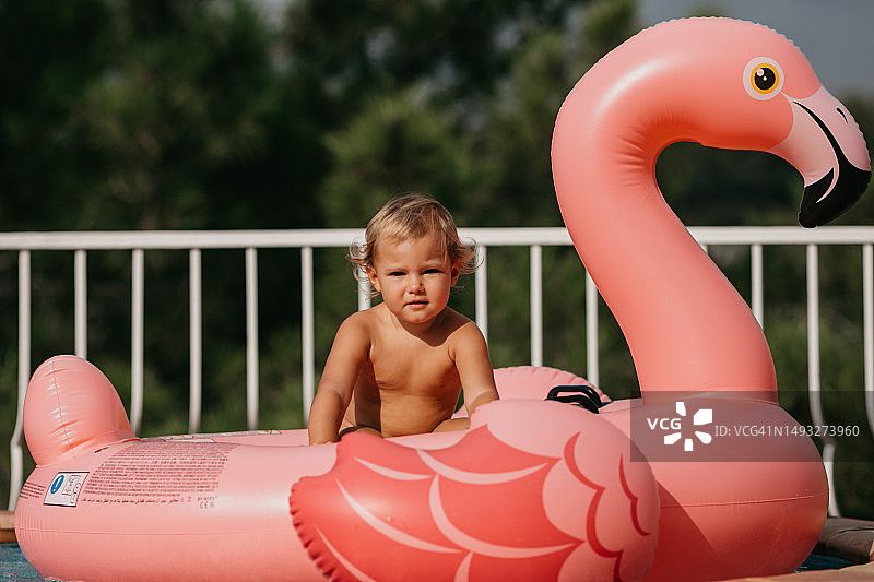坐在粉色火烈鸟充气玩具上的幼儿图片素材