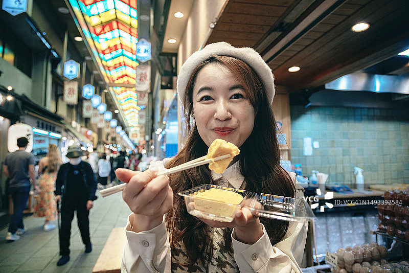 在京都锦市场品尝当地美食的亚洲女性图片素材