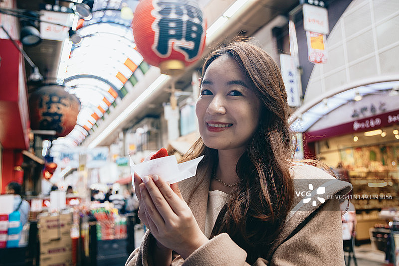 亚洲女性在日本大阪观光，在黑门市场品尝当地美食图片素材